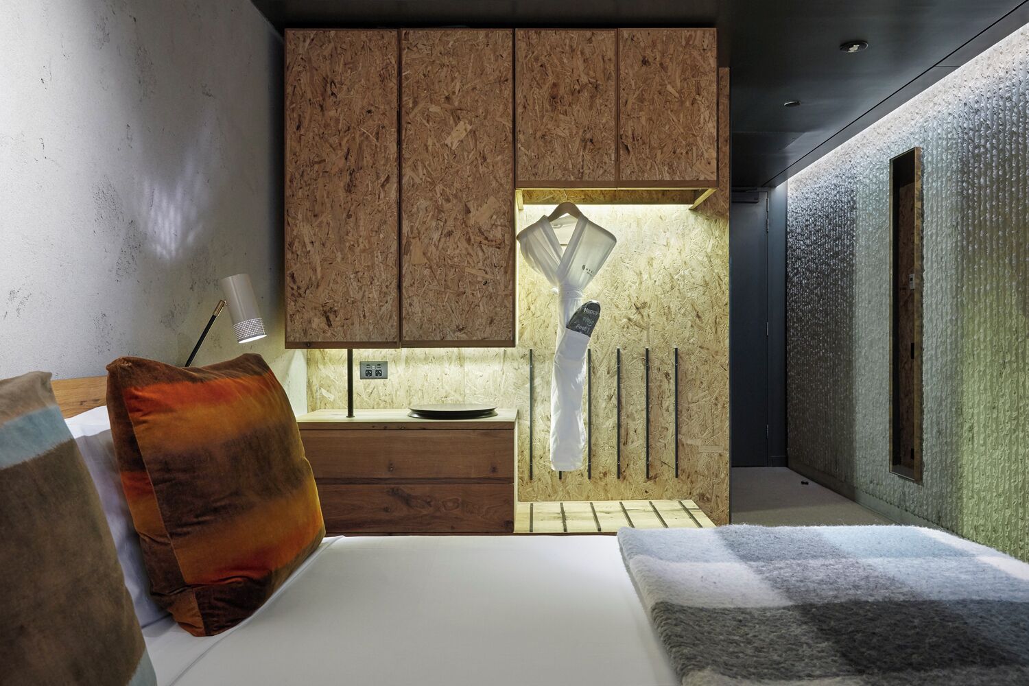 A modern bedroom with a wooden headboard, a bedside table, and a large bed.