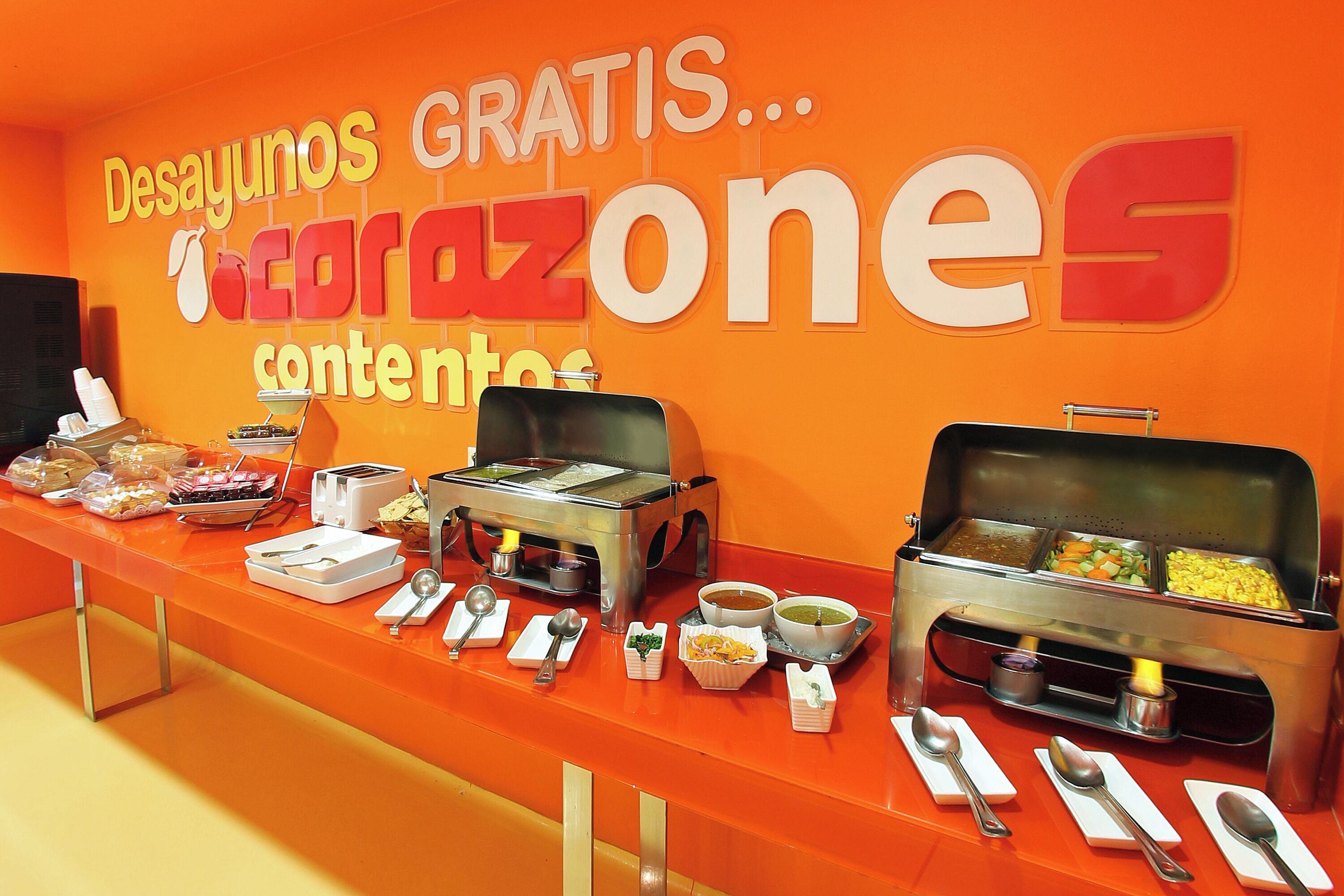 Ein Buffet mit verschiedenen Speisen und Besteck auf einer leuchtend orangefarbenen Theke.