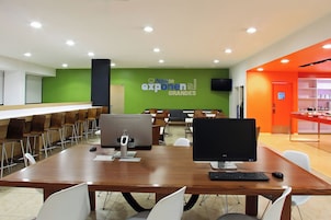 A conference room with a long table, chairs, computers, and a green wall with signage.