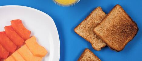 A plate with slices of toast and carrot sticks on a blue background.
