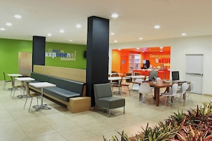 A modern waiting area with a green wall, a reception desk, and multiple seating options including a bench and chairs.