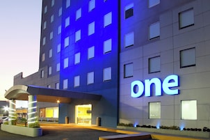 A hotel with a prominent 'one' sign, a covered entrance, and a well-lit facade.