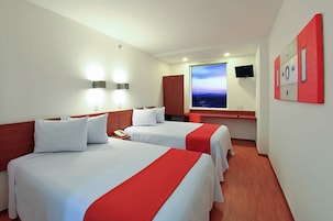 A hotel room with two beds, a window with a view, a flat-screen TV, and a red artwork on the wall.
