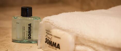 A bottle of SOMMA soap and a bar of SOMMA soap on a beige surface.