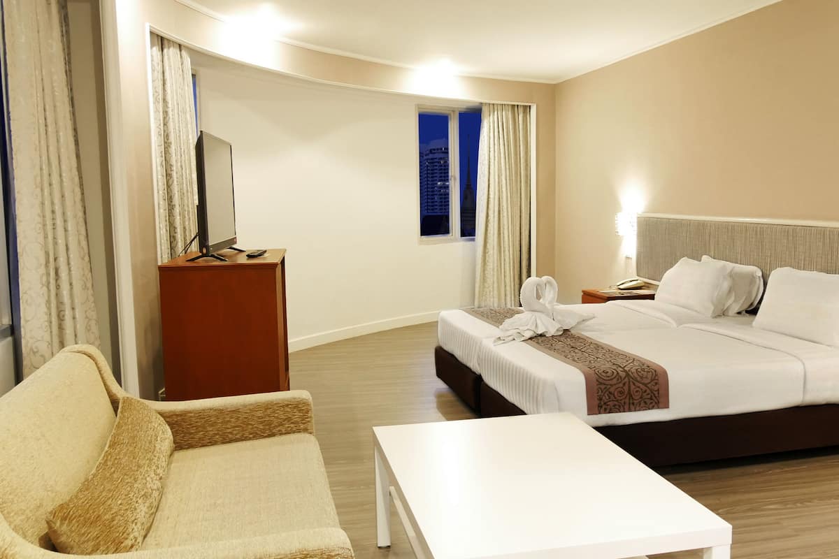 Une chambre d’hôtel équipée d’un lit, d’un bureau, d’une chaise, d’une télévision et offrant une vue sur le paysage urbain.
