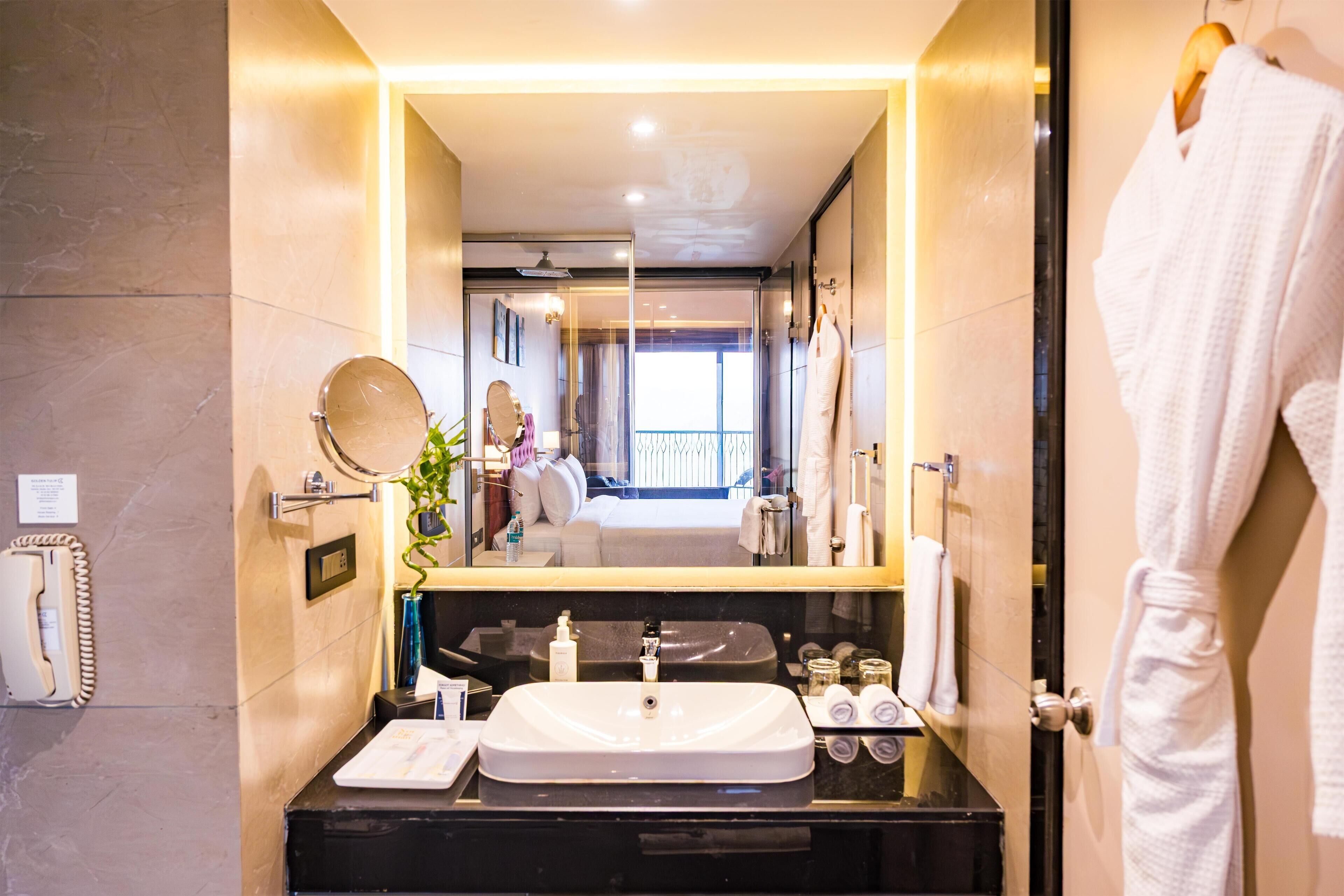 A modern bathroom with a large mirror, a sink, and a robe hanging on the wall.