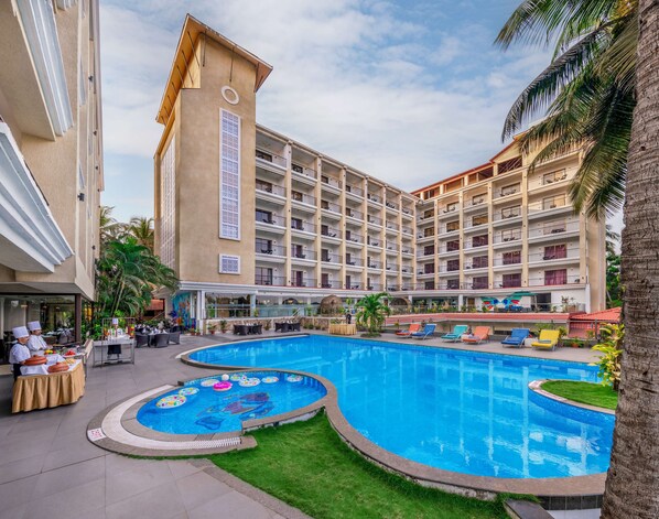 A hotel with a large pool area, multiple balconies, and a restaurant serving food. - Golden Tulip Goa Candolim (Candolim)