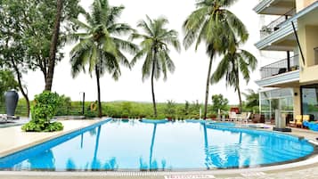 A swimming pool with a 'No Diving' sign, surrounded by palm trees and a building with balconies.