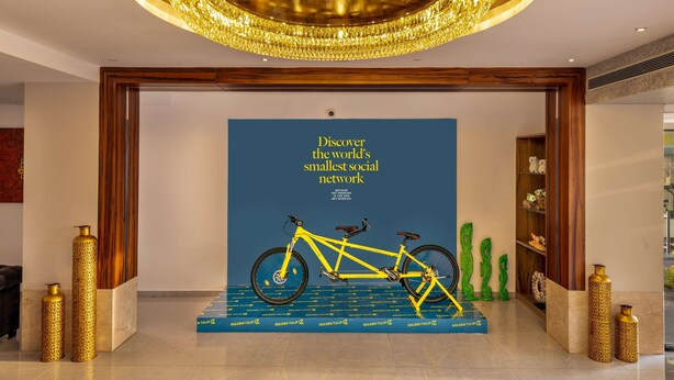 A modern lobby with a large chandelier, a bicycle display, and a blue wall with text. - Golden Tulip Goa Candolim (Candolim)