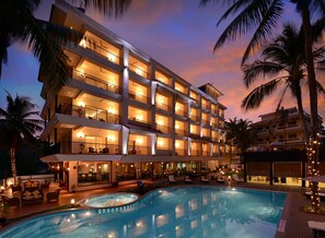 A multi-story hotel with a swimming pool, outdoor seating, and palm trees. - Golden Tulip Goa Candolim (Candolim)