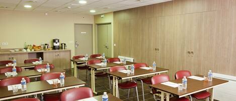 A conference room with multiple tables and chairs, equipped with water bottles and papers.