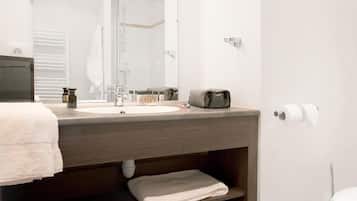 Un baño moderno con un espejo grande, un lavamanos, un perchero para toallas y un inodoro.