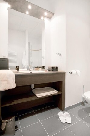 Un baño moderno con un espejo grande, un lavamanos, un perchero para toallas y un inodoro.