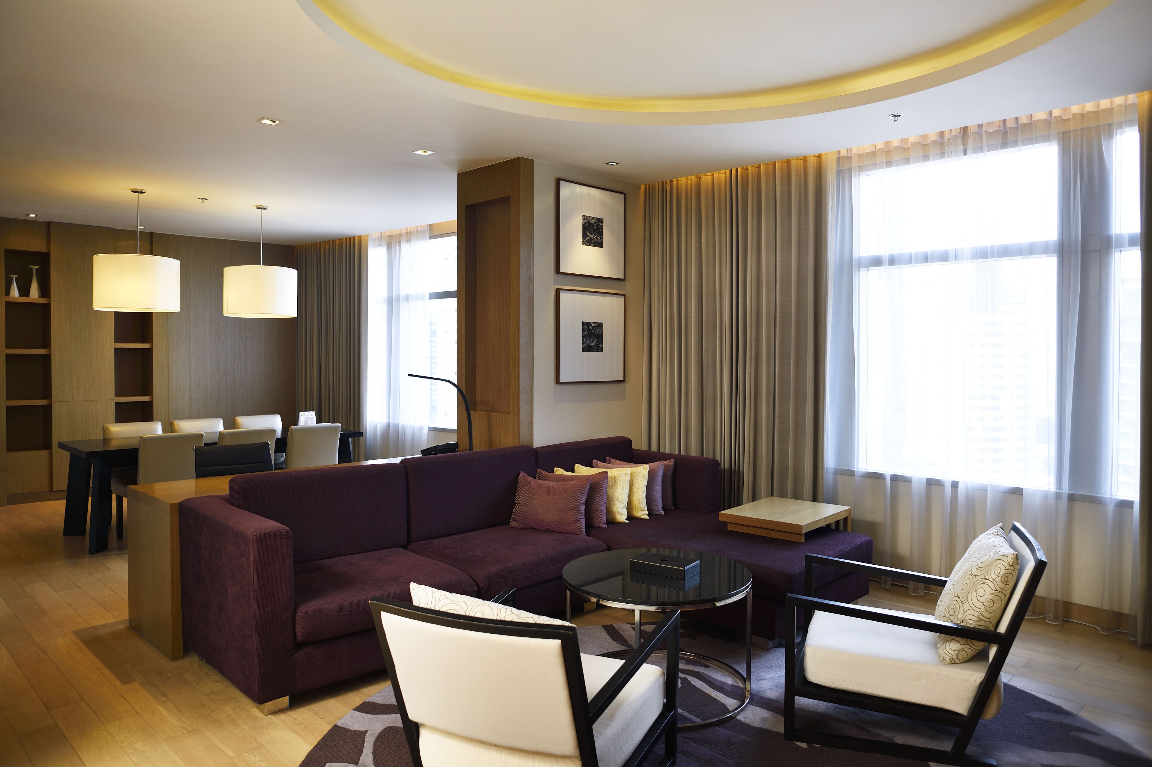 Una sala de estar moderna con sofá, sillones, una mesa de centro y un comedor con mesa y sillas.