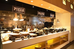 Een keukenruimte met borden waarop 'PIZZA' en 'PASTA' staan, wat aangeeft dat er eten wordt bereid.