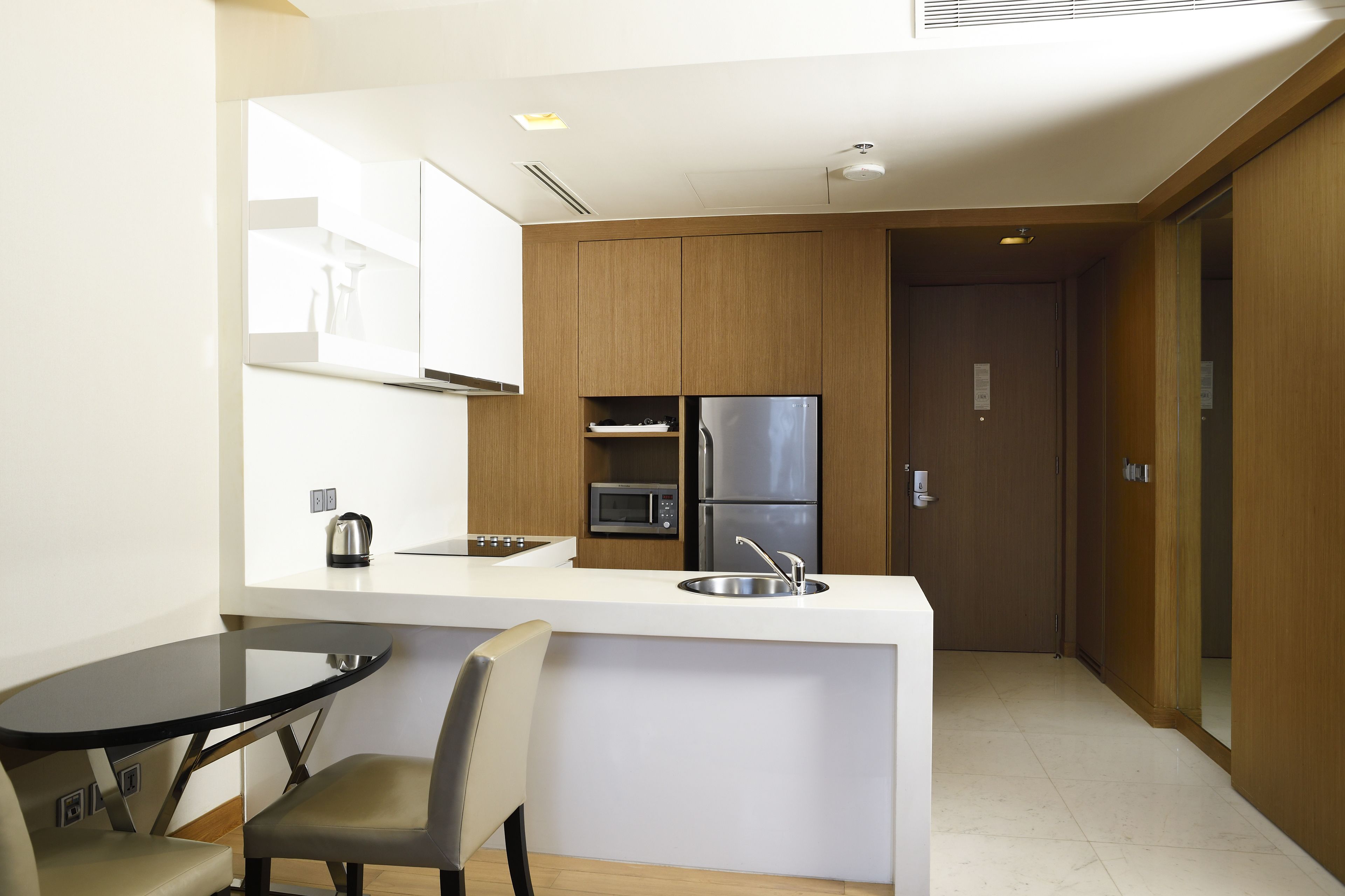 A modern kitchen with a central island, stainless steel appliances, and a dining area with a glass table and chairs.