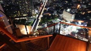 A high-rise building with a glass balcony overlooking a cityscape at night. - Marriott Bangkok Sukhumvit (Bangkok)