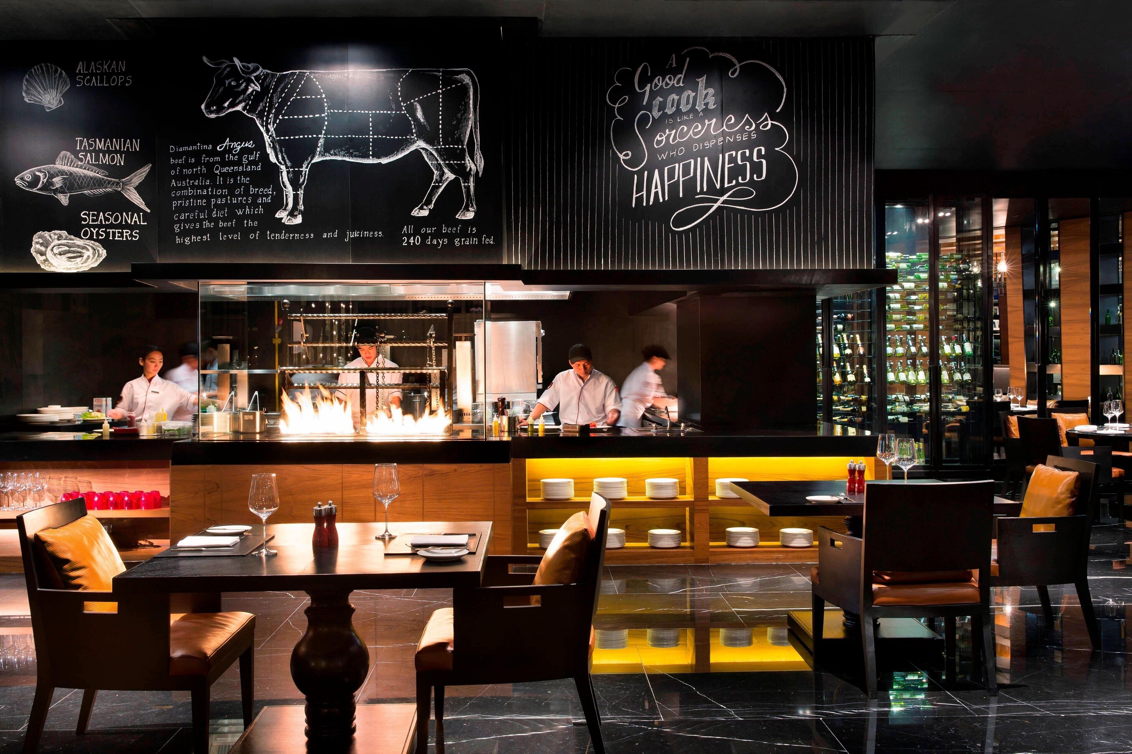 Un restaurante con zona de bar, un chef preparando comida y un menú que muestra opciones de mariscos y carne.
