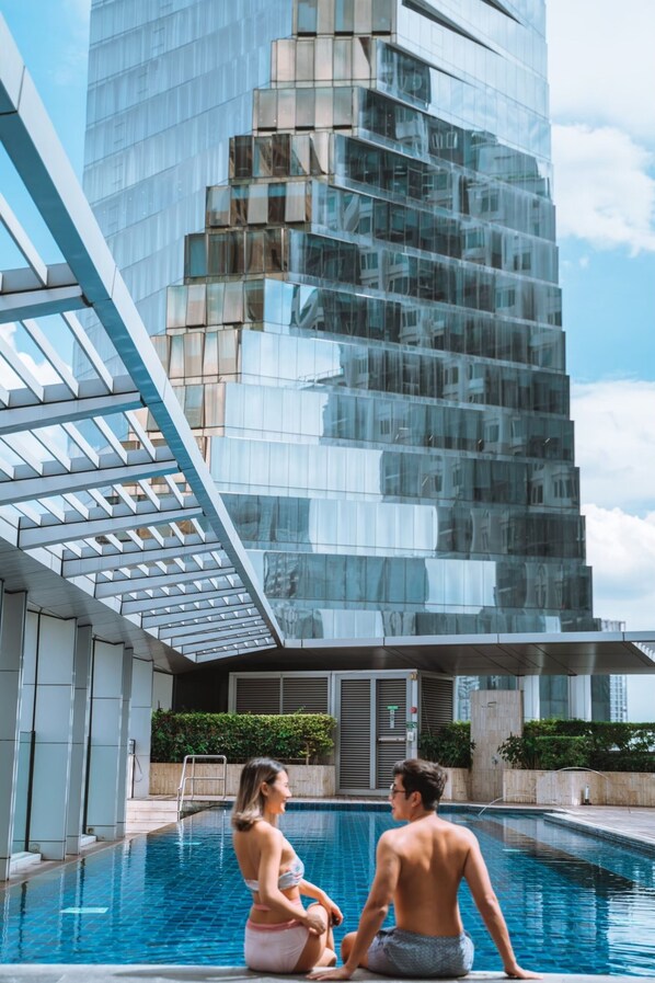 A modern building with a glass facade and a pool area.