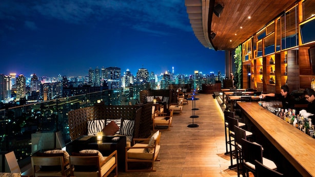 A rooftop bar with a city skyline view, wooden flooring, and bar stools. - Marriott Bangkok Sukhumvit (Bangkok)