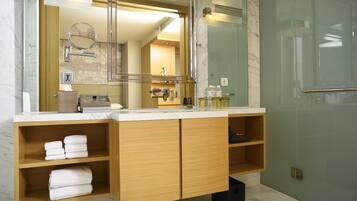 A modern bathroom with a large mirror, marble countertop, wooden cabinets, and a glass shower enclosure.