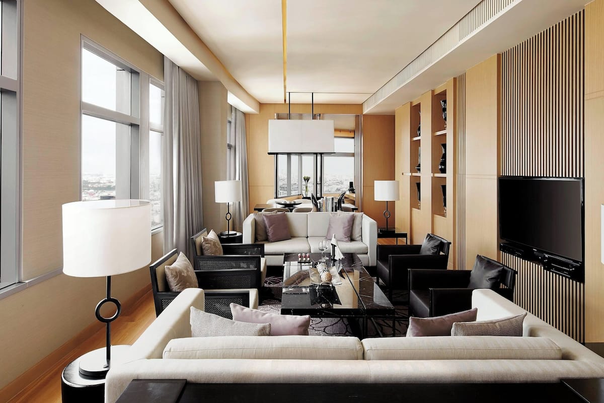 Habitación de hotel moderna con un sofá grande, una mesa de comedor y un televisor de pantalla plana.