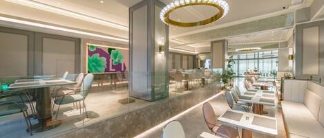 A modern hotel lobby with a central seating area, glass partitions, and a large window providing natural light.