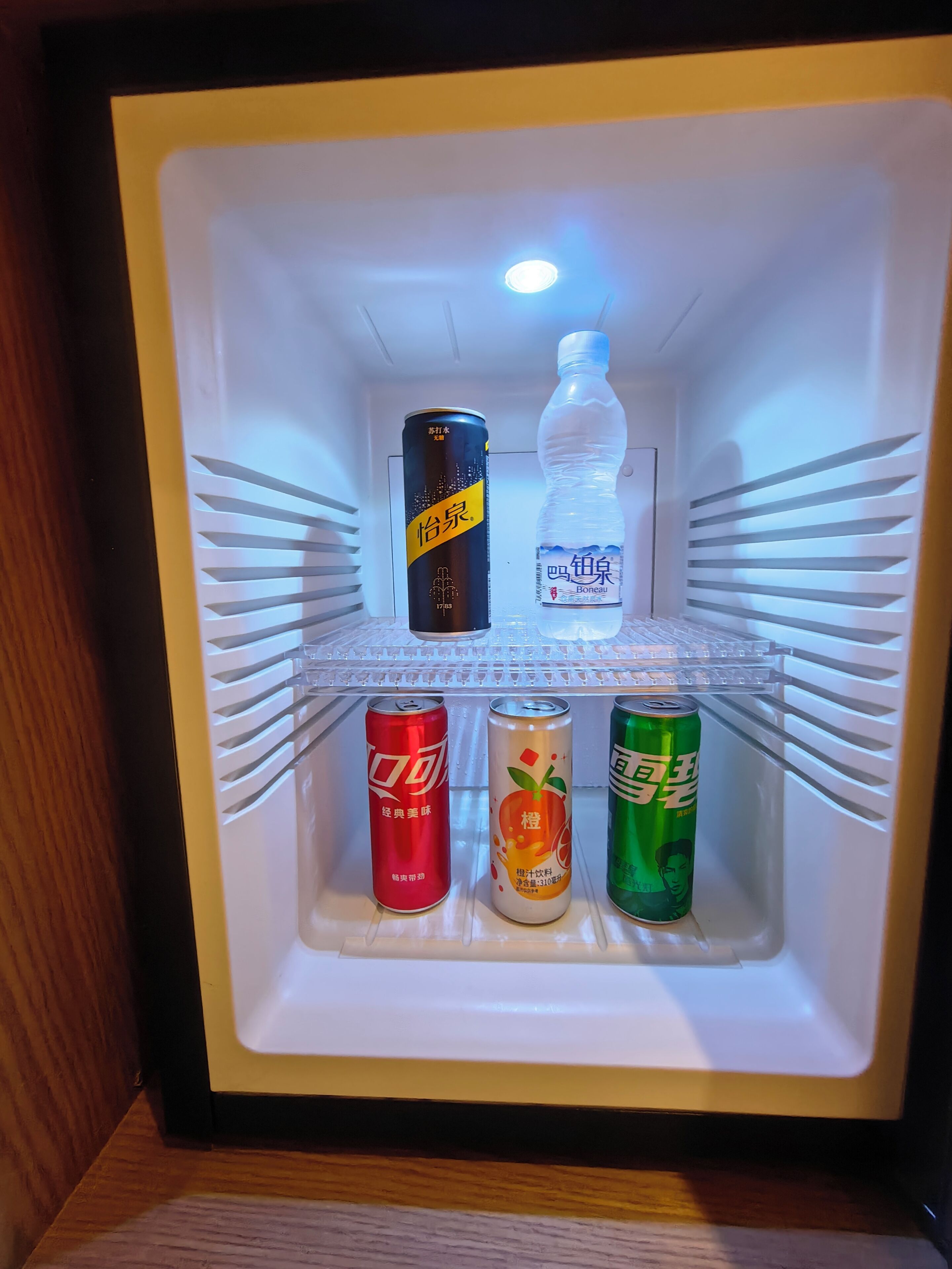 A refrigerator with beverages and a bottle.
