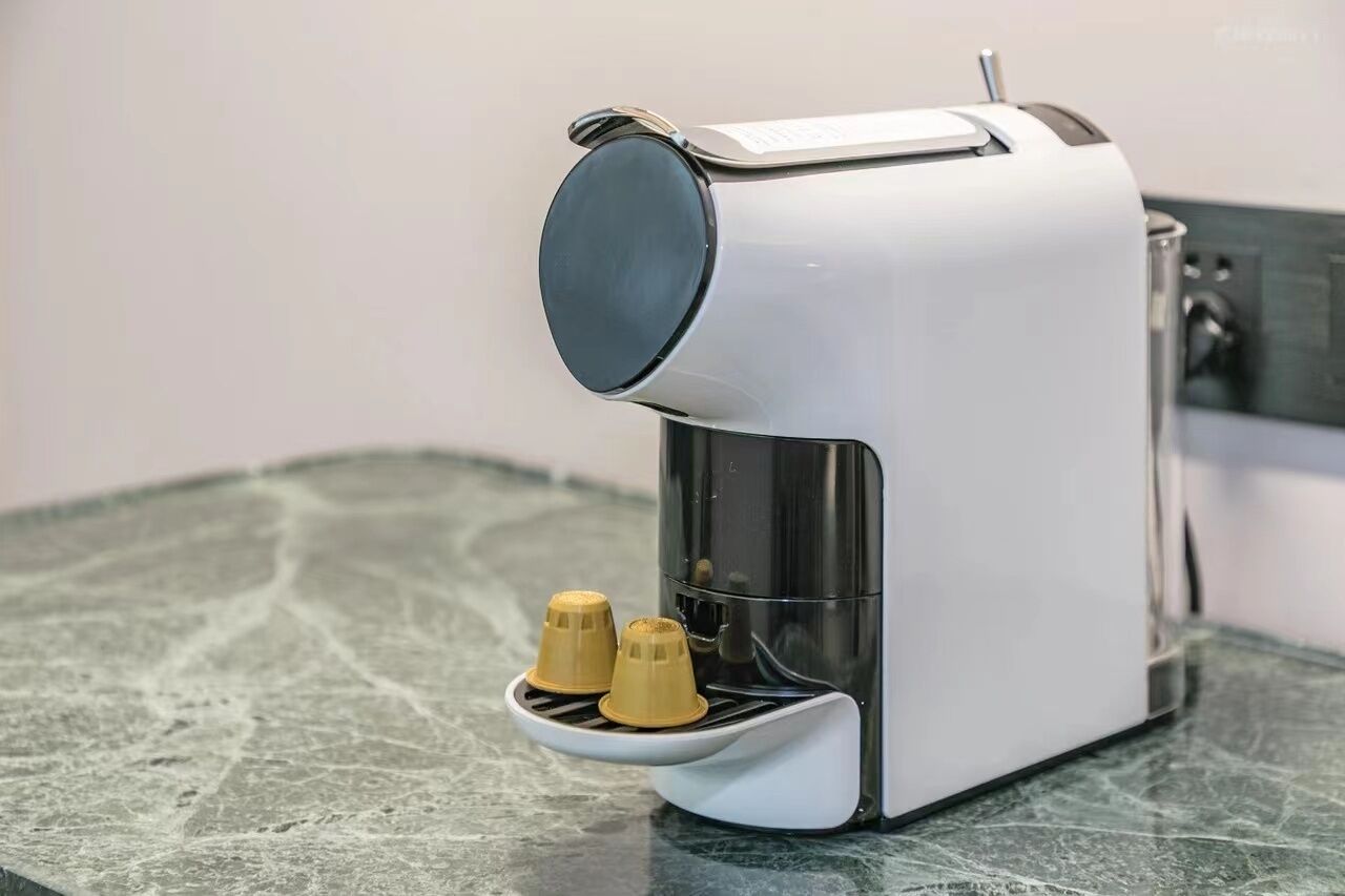 A coffee machine with a single cup holder on a marble countertop.