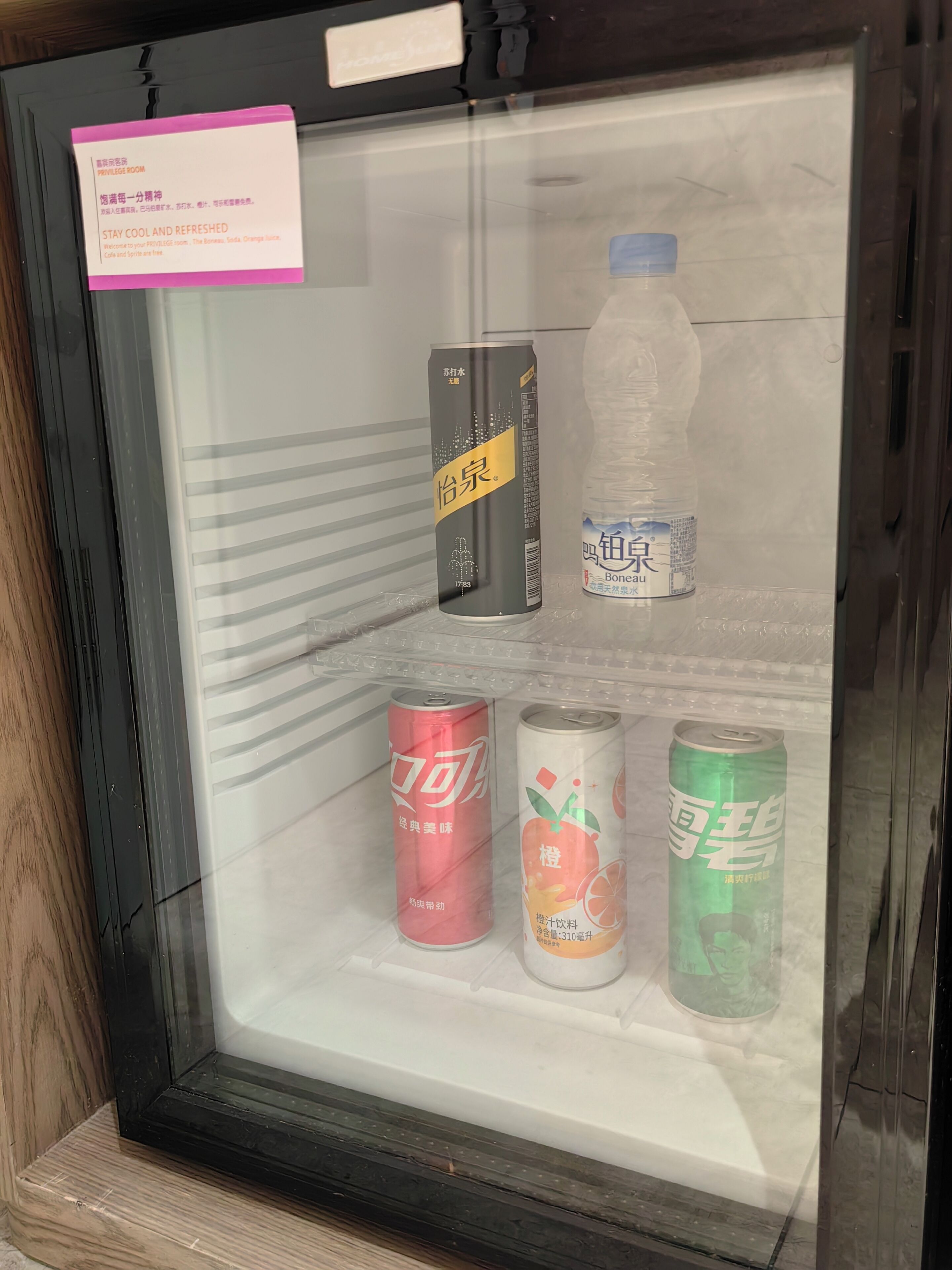 Vitrina refrigerada con bebidas, incluyendo una lata de té helado, una botella de agua y latas de refresco.