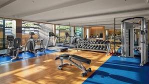 A modern gym with cardio machines, free weights, and a bench.