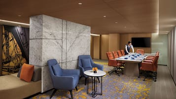 A modern conference room with a marble partition, blue chairs, a round table with a white base, and a colorful carpet.