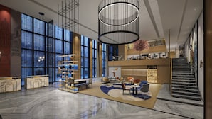 A spacious lobby with a marble floor, a central seating area, and a staircase leading to an upper level.