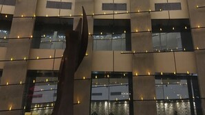 Een gebouw met verschillende gebogen ramen en een hand die naar het plafond reikt.