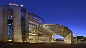 Een modern hotel met een gebogen glazen gevel en een overdekte ingang.