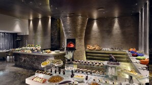 Een buffet met diverse gerechten, een centrale bakoven en een modern interieur.