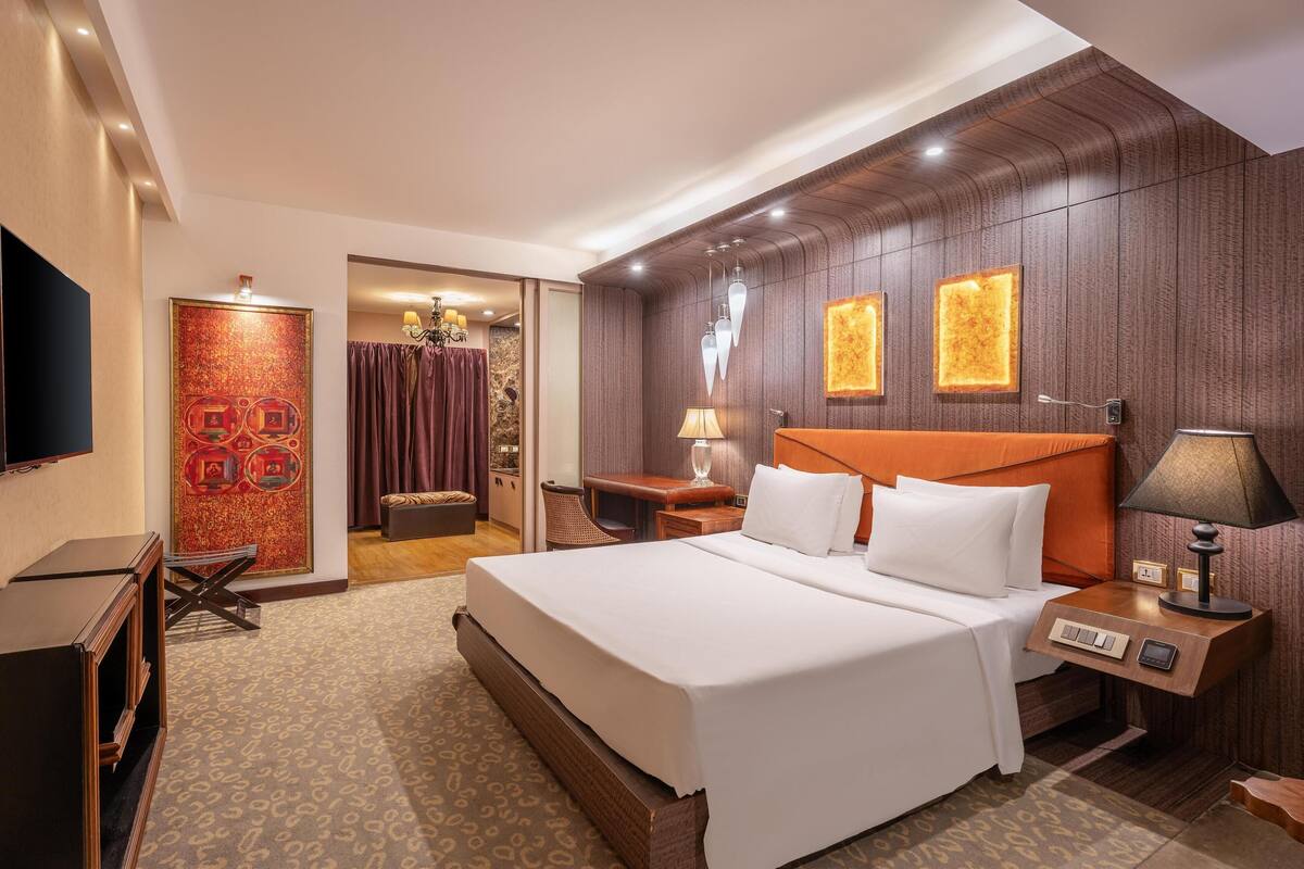 Une chambre d’hôtel avec un grand lit, un bureau, une télévision et une porte donnant sur une salle de bain.