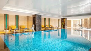 Ein Innenpool mit klarem, blauem Wasser, gelben Liegestühlen und einem modernen Design.