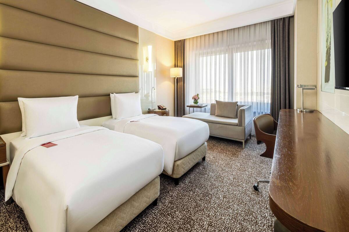 Ein Hotelzimmer mit zwei Betten, einem Schlafsofa, einem Schreibtisch und einem Fernseher.