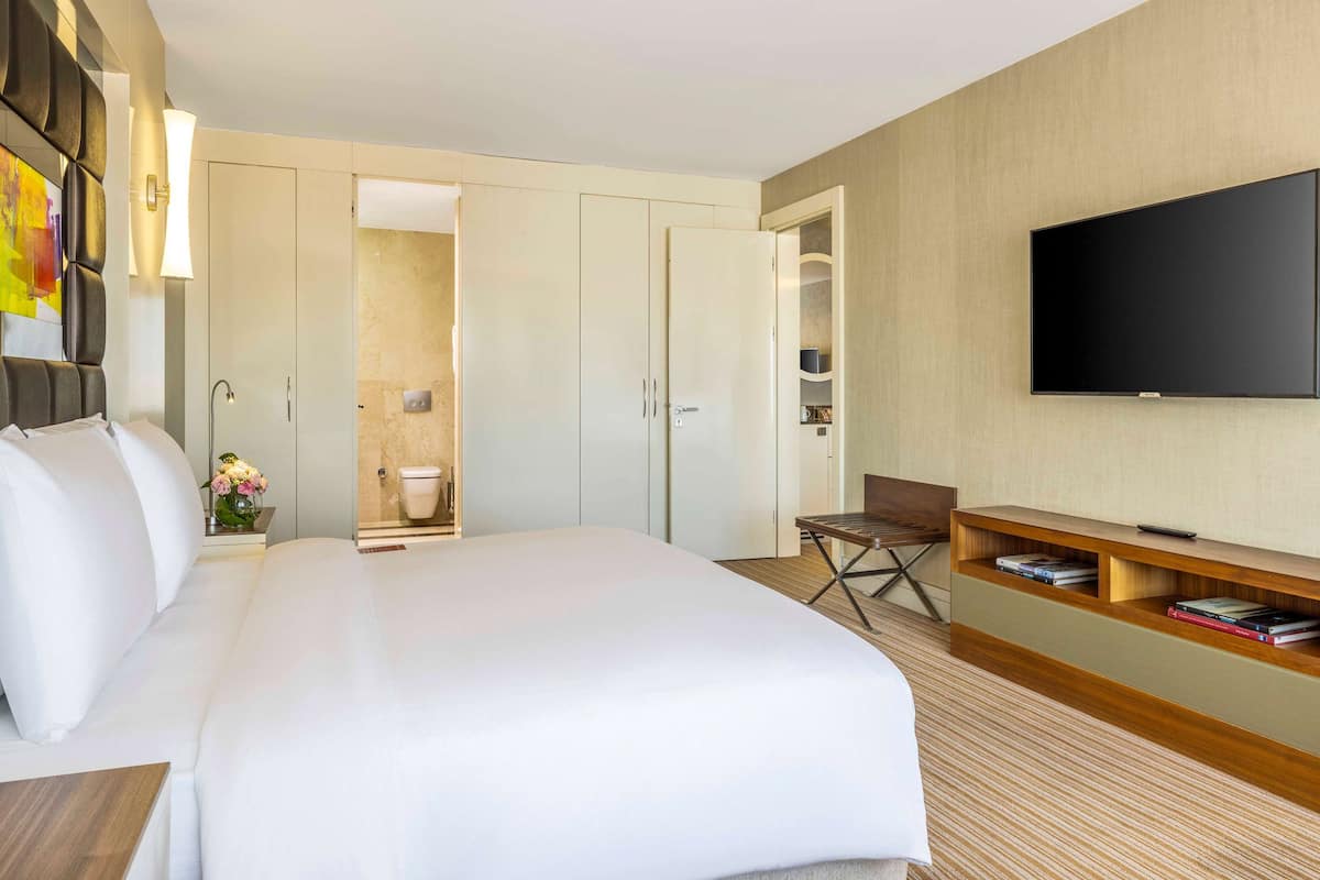 Ein Hotelzimmer mit einem großen Bett, einem Fernseher, einem Schreibtisch und einem Kleiderschrank.