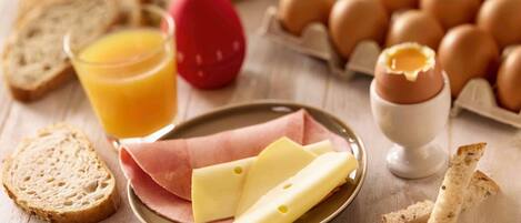 A breakfast setting with bread, eggs, cheese, and a glass of orange juice.