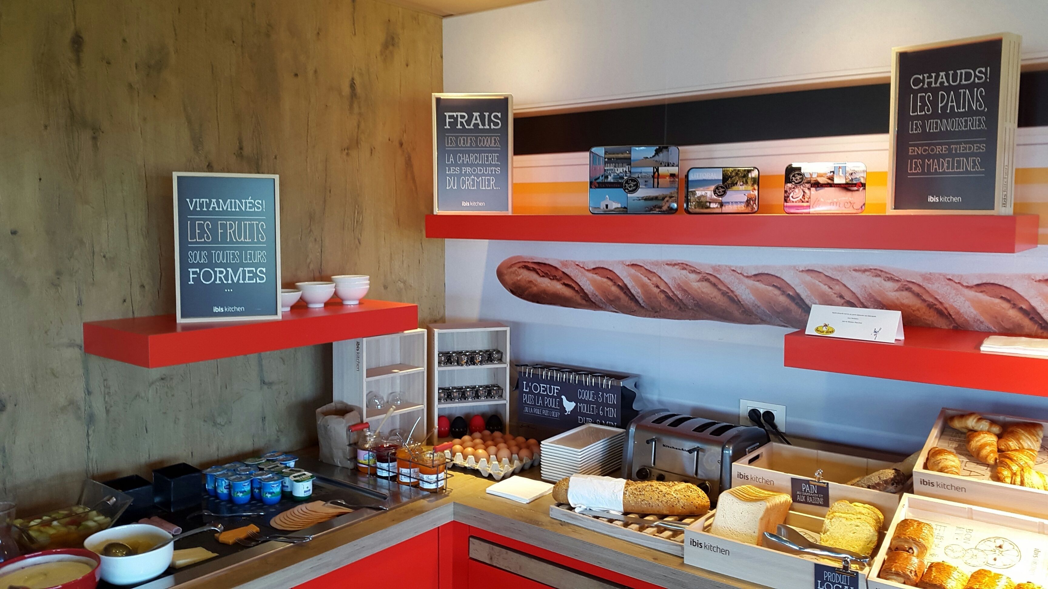 Een bakkerijdisplay met diverse gebakken producten en een bord waarop verse broden, taarten en gebak worden aangeboden.