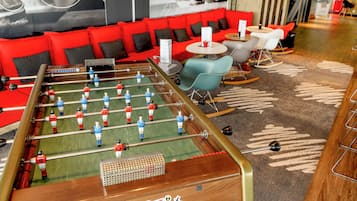 Una mesa de fútbol de mesa en un salón moderno con sofás rojos y una alfombra estampada.