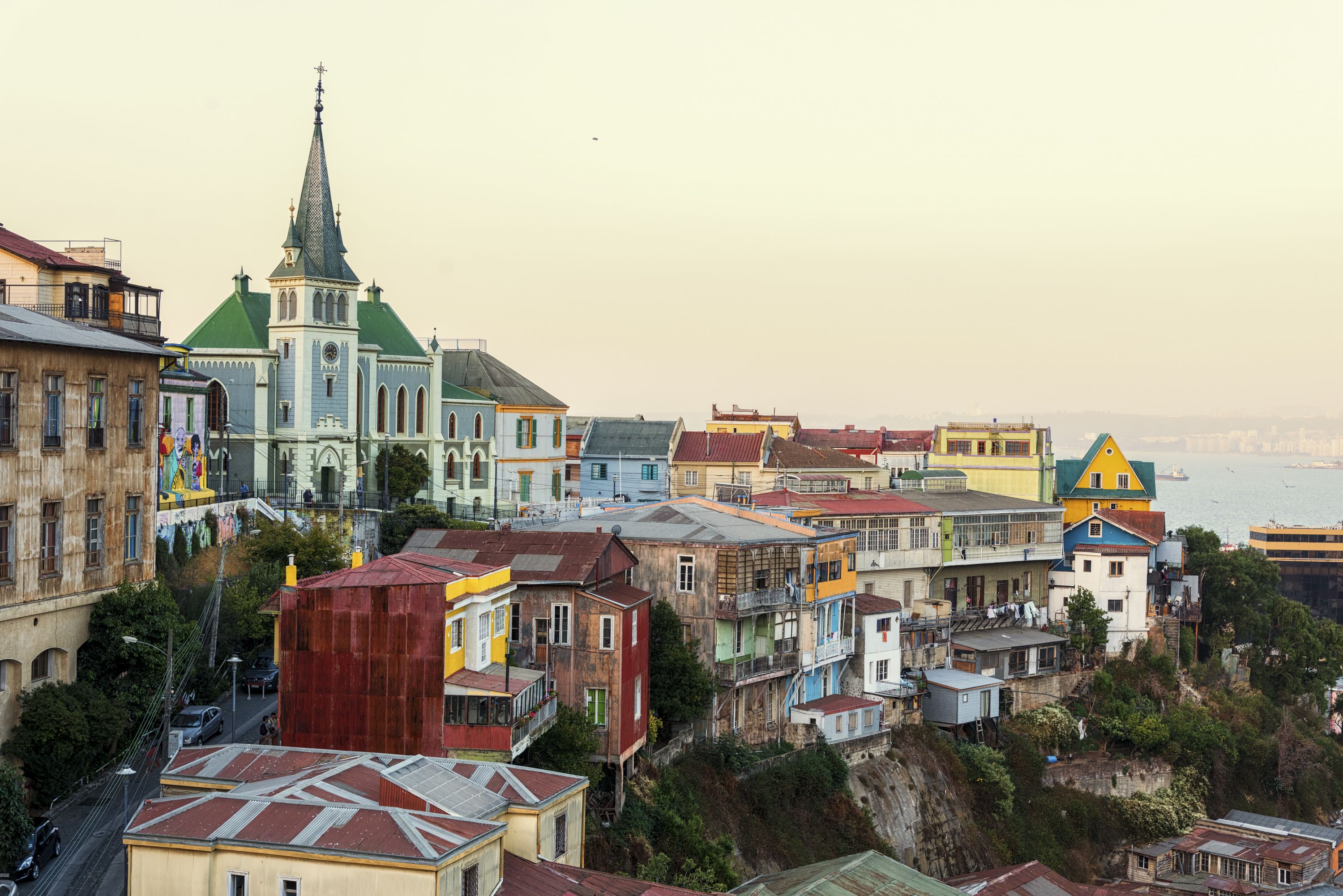 A coastal town with colorful buildings, a prominent church with a spire, and a view of the sea.