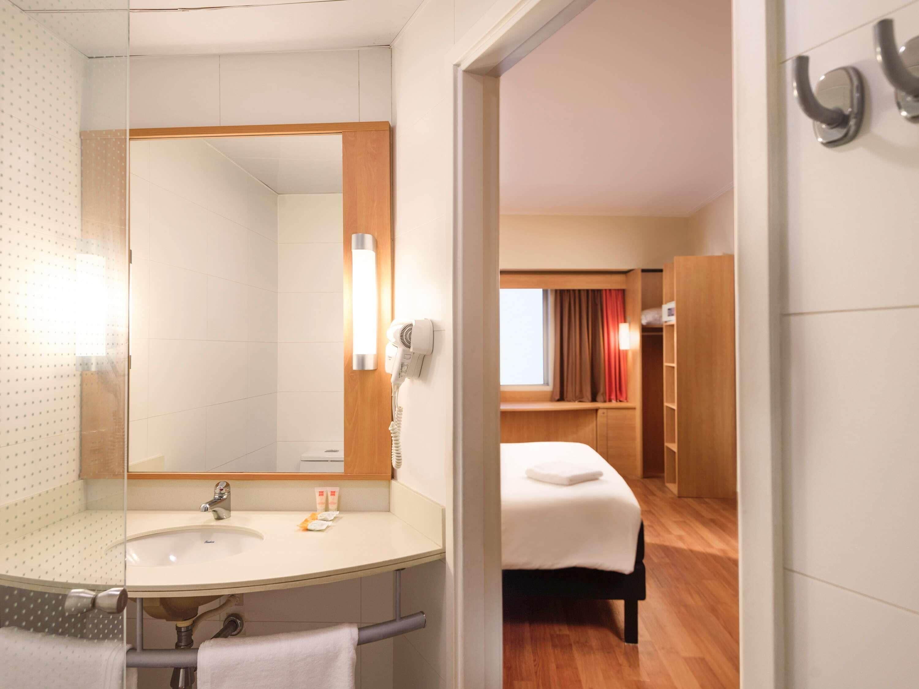 Un baño de hotel con lavabo, espejo y perchero para toallas.