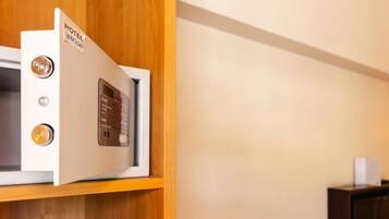 A hotel room with a wooden cabinet, a thermostat, and a small shelf.