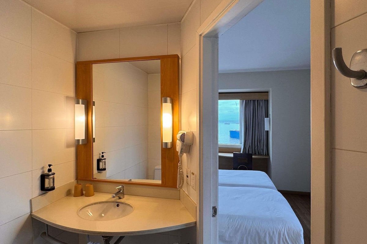 A hotel bathroom with a sink, mirror, and toiletries.