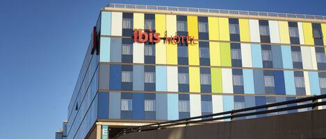 A multi-story hotel with a colorful facade and the name "ibis HOTEL" prominently displayed.