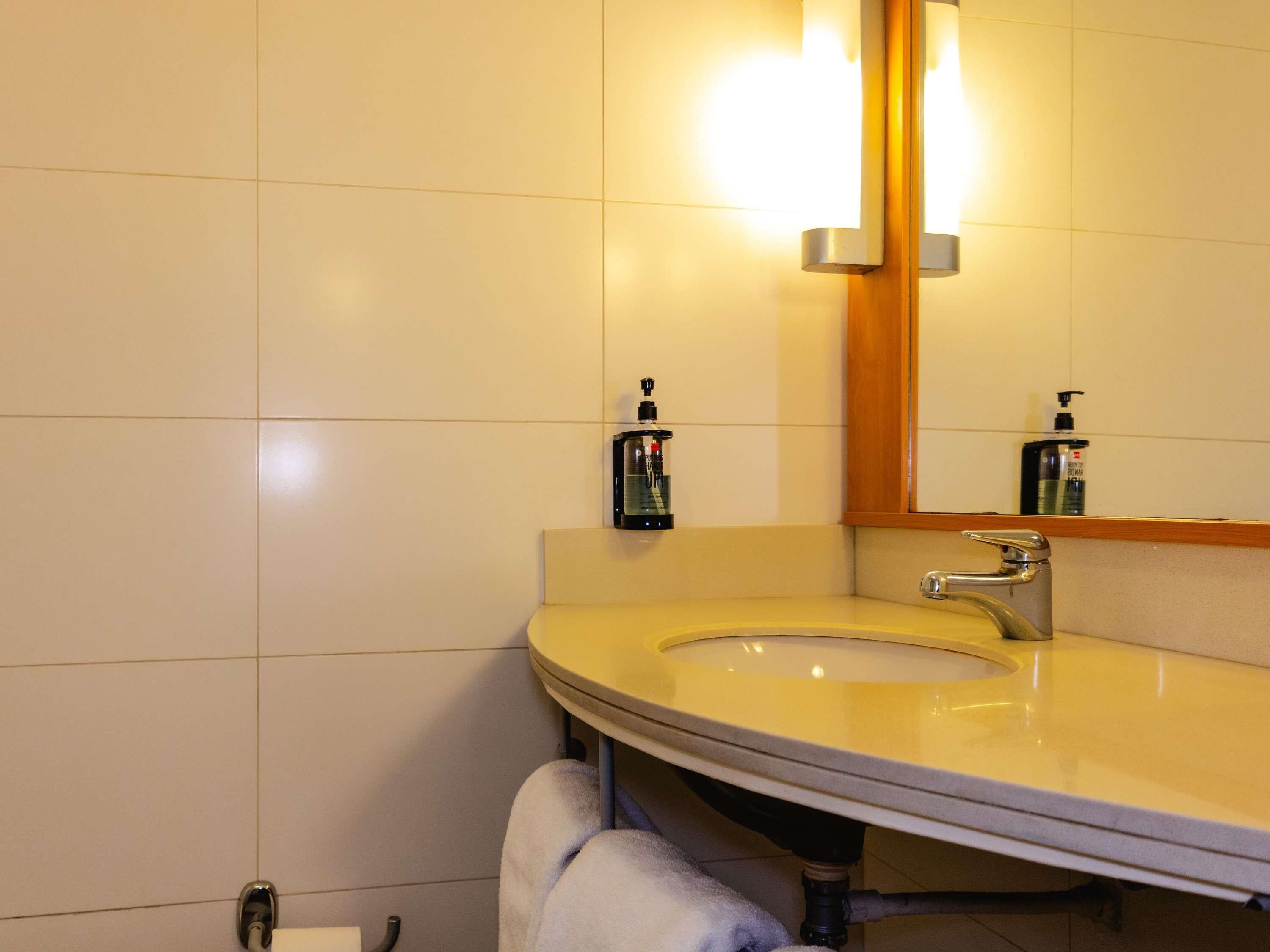 Un baño con lavabo, espejo y toallero.