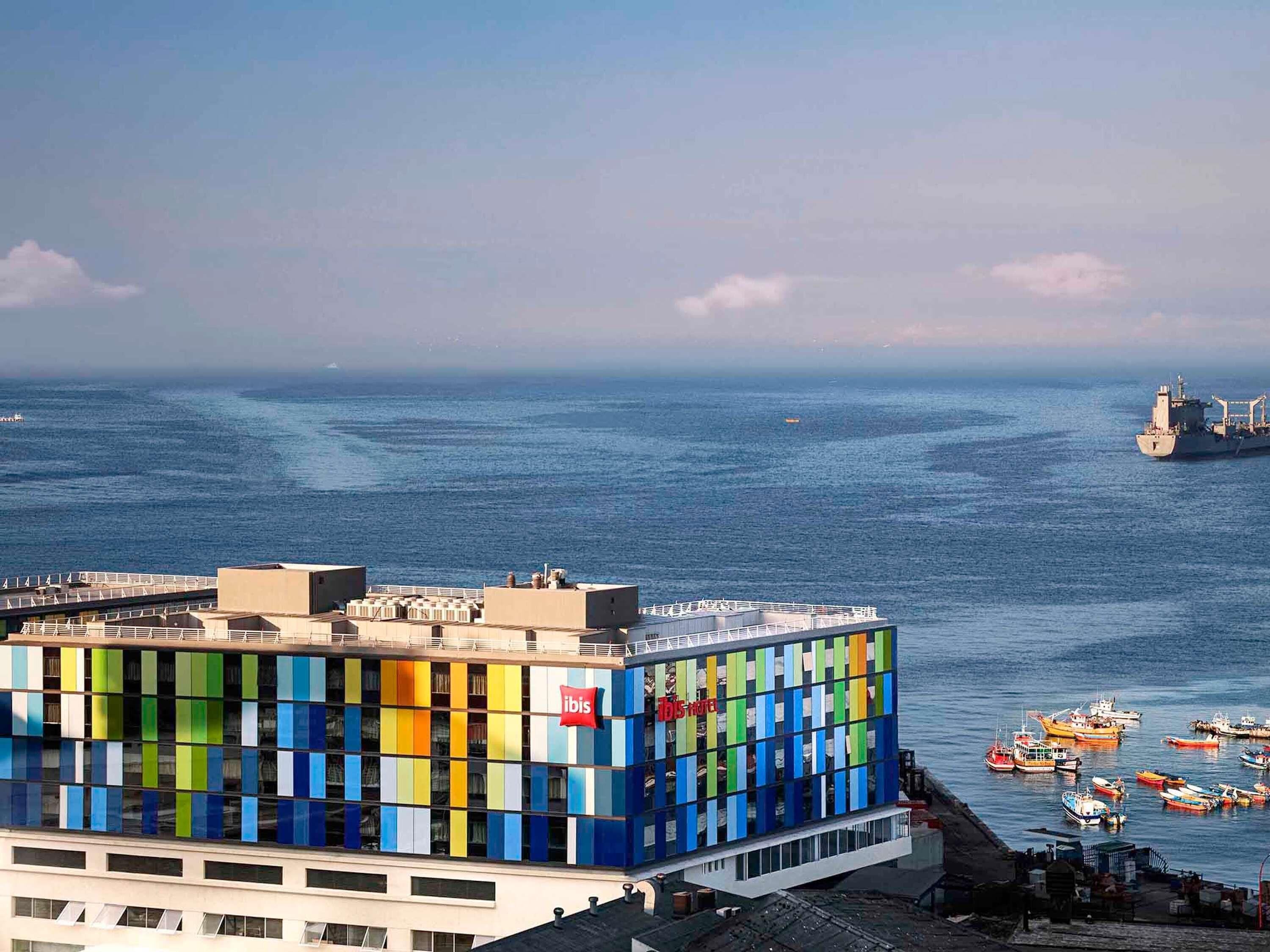 Un edificio moderno con fachada colorida, cerca de un cuerpo de agua con barcos.